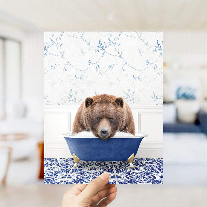 A brown bear sitting in a blue bathtub, surrounded by a floral patterned wall.