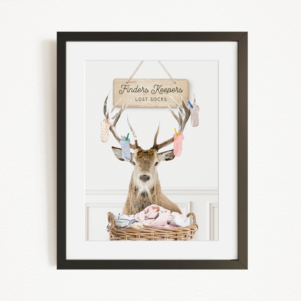 A deer with antlers sits in a basket filled with socks, with a sign above that reads "Finders Keepers Lost Socks".