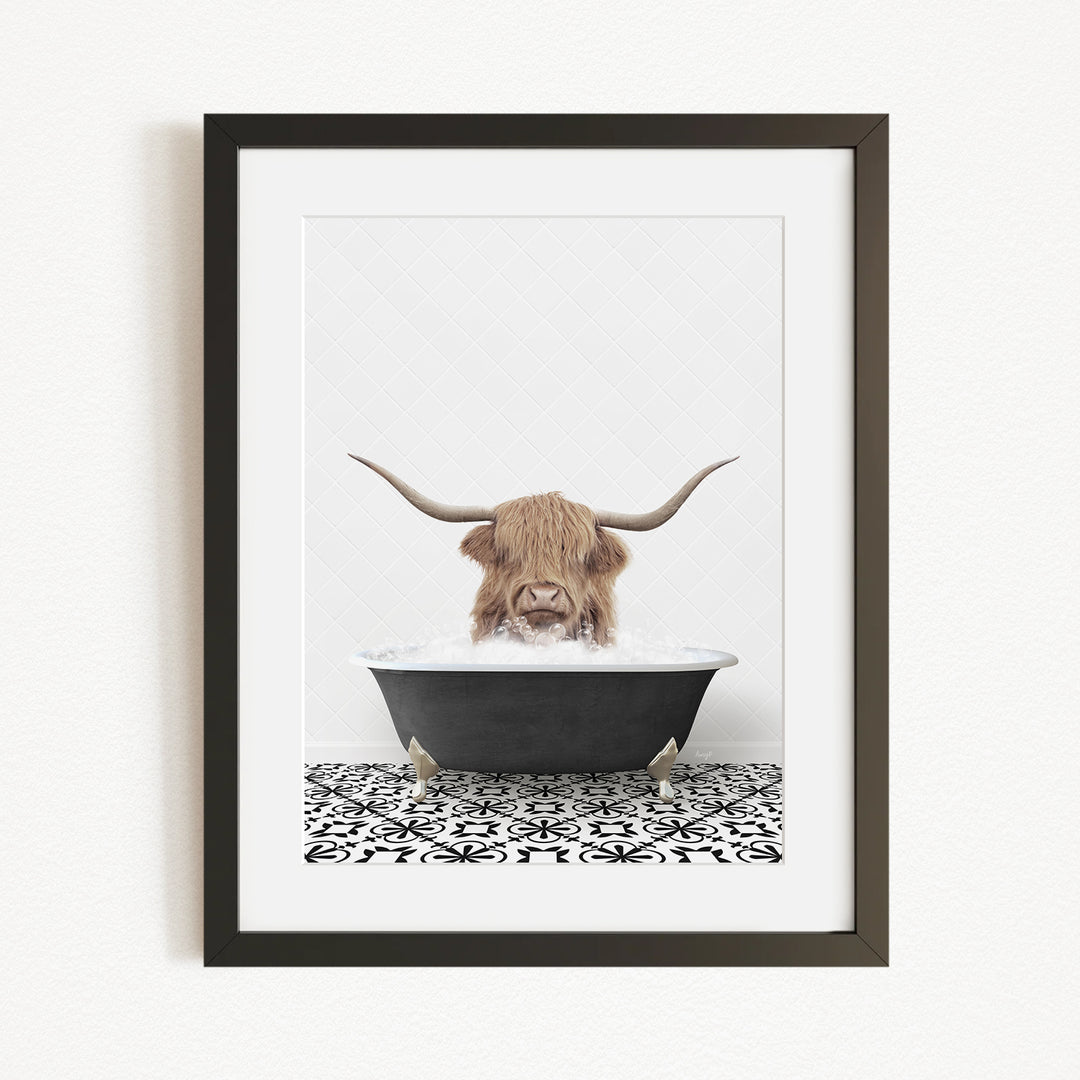 A framed image depicting a Highland cow with long horns sitting in a bathtub filled with water.