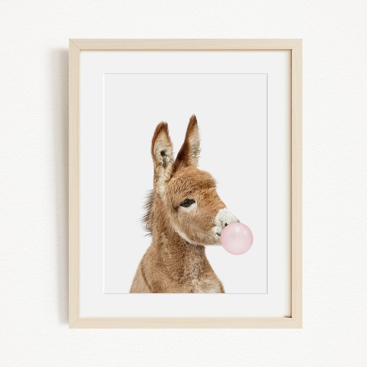 A picture of a donkey blowing a bubble with a pink bubble gum bubble.