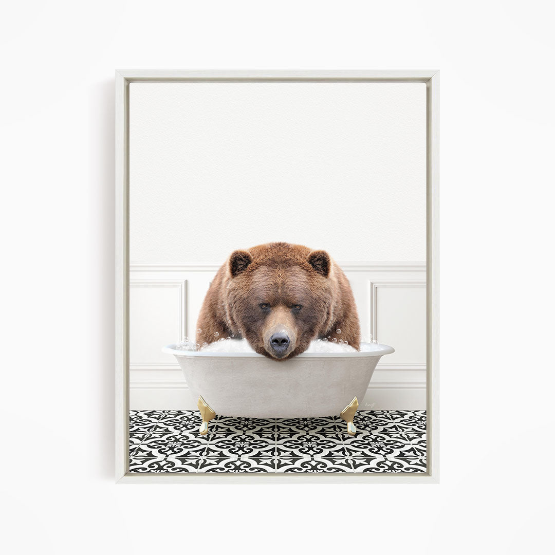 A brown bear is sitting in a white bathtub filled with water, appearing to enjoy the bath.