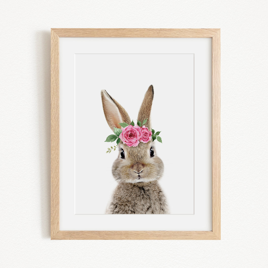 A framed print of a rabbit wearing a floral crown of pink roses.