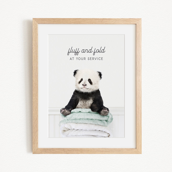 A panda bear sitting on a stack of towels, with the text "fluff and fold at your service" written above the image.