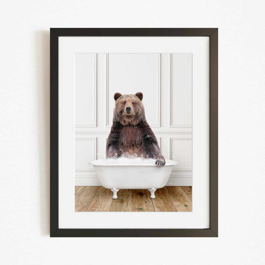 A brown bear sitting in a white bathtub filled with water, with a wooden floor beneath it.