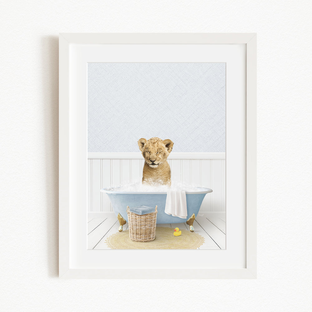 A young lion cub sitting in a blue bathtub filled with water, surrounded by rubber ducks and a basket.