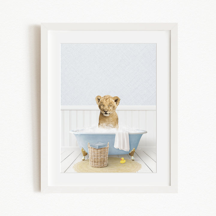 A young lion cub sitting in a blue bathtub filled with water, surrounded by rubber ducks and a basket.