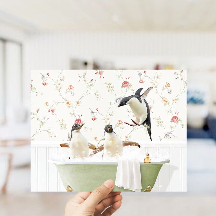 A hand holds up a collage of three images depicting penguins in a bathtub, with one penguin flying out of the tub.