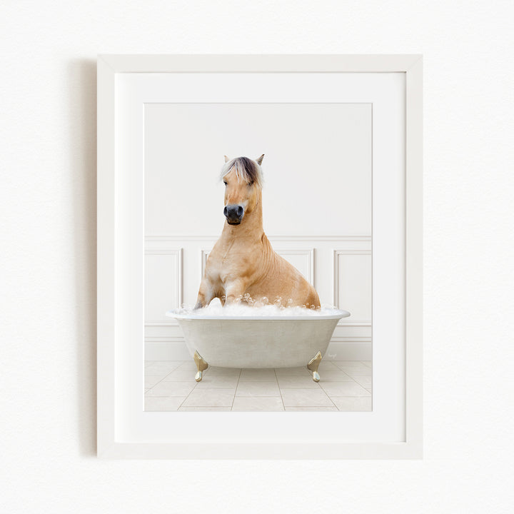A light brown horse is sitting in a white bathtub filled with bubbles, creating a whimsical and playful scene.