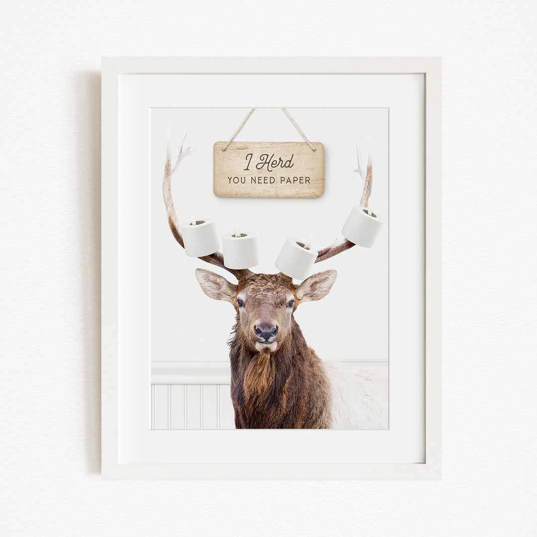 A framed image of a deer with antlers, displaying a sign that says "I herd you need paper".