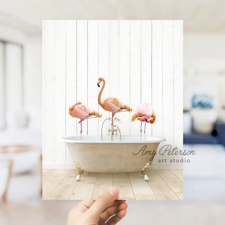 a person holding a photo of three flamingos in a bathtub