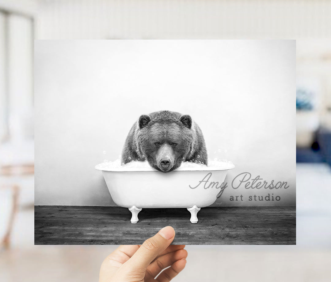 a hand holding up a black and white photo of a bear in a bathtub