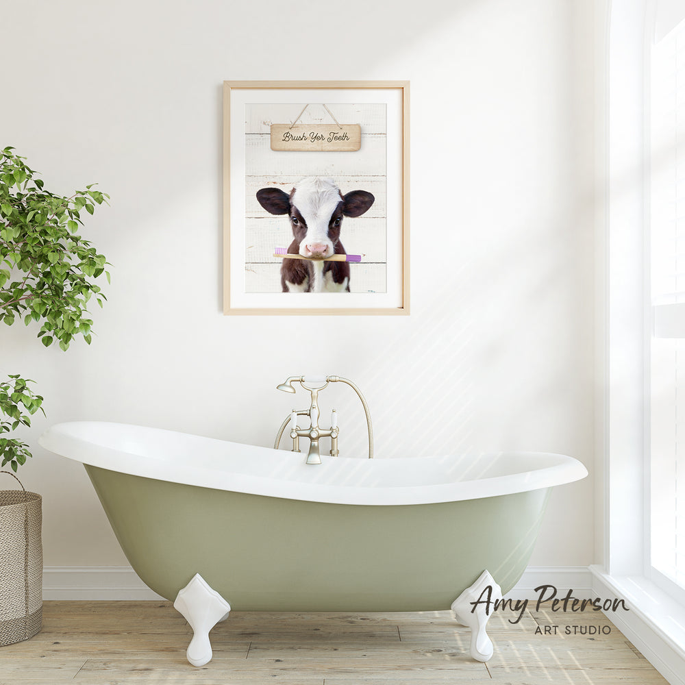 a green clawfoot bathtub with a framed picture of a cow hanging above it. The bathroom has a white wall and a window, creating a serene and relaxing atmosphere.