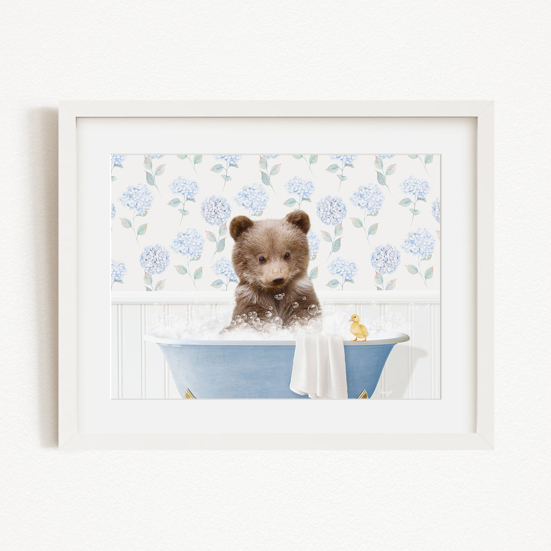 A brown bear sitting in a blue bathtub filled with bubbles, with a yellow rubber duck floating nearby.