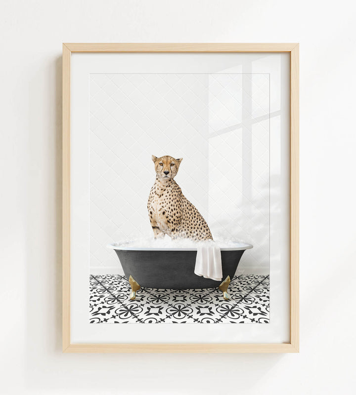 A cheetah sitting in a black bathtub filled with bubbles, with a white towel hanging on the side of the tub.