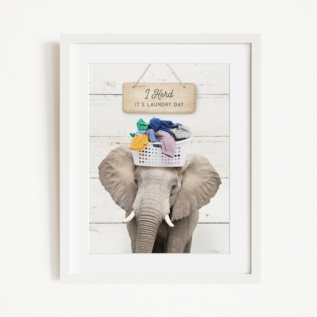 A framed image of an elephant holding a basket of laundry, with a sign above it that says "I Harded It's Laundry Day".