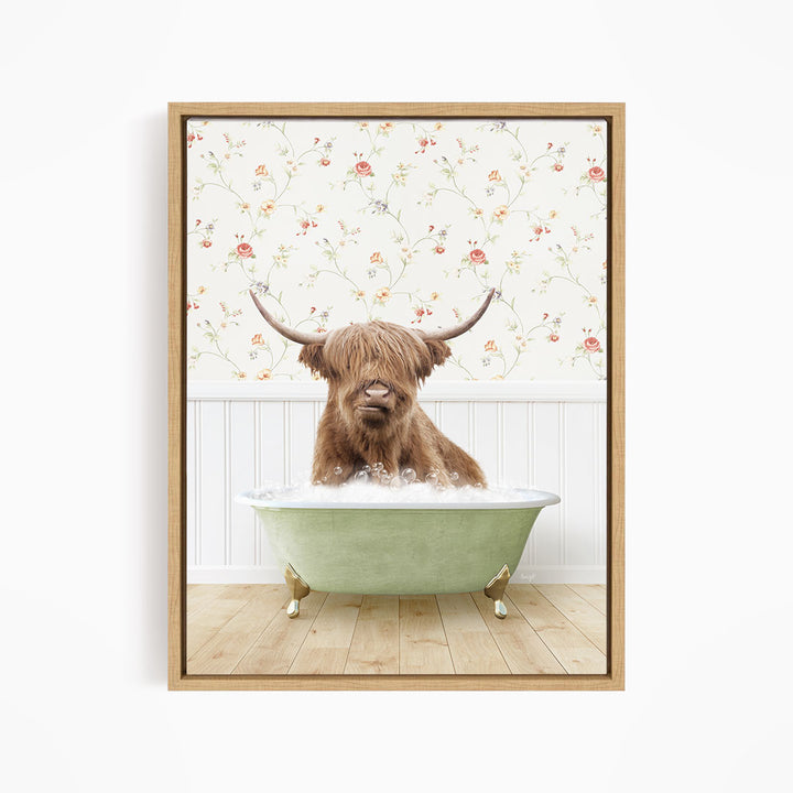 A brown cow with long horns is sitting in a green bathtub filled with water, with a floral wallpaper in the background.