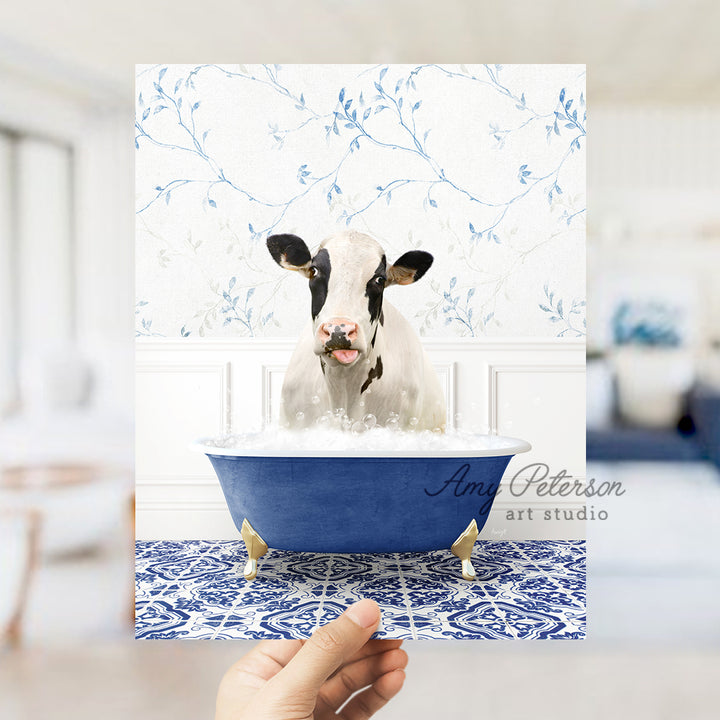 a hand holding a card with a picture of a cow in a bathtub