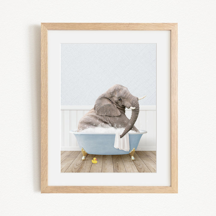 A gray elephant is sitting in a blue bathtub filled with water, surrounded by yellow rubber duckies.