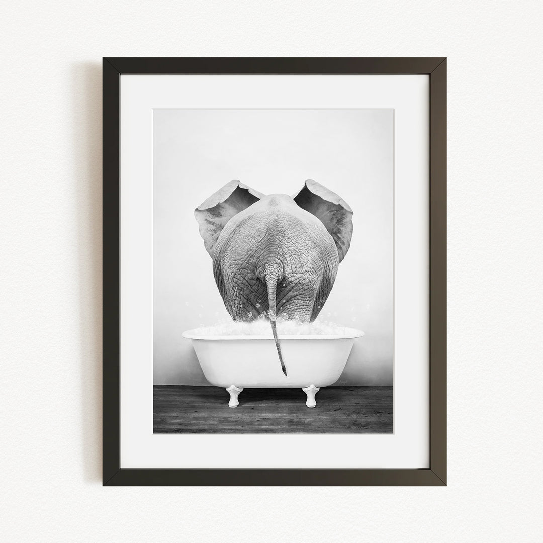 A black and white photograph of an elephant standing in a bathtub filled with water, with its trunk submerged in the water.