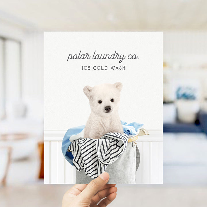 A hand holding a white polar bear in a laundry basket, with the text "polar laundry co. ICE COLD WASH" displayed above the image.