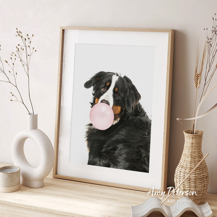 A framed photograph of a dog blowing a bubble with a pink bubble gum bubble, accompanied by decorative vases and a text that reads " Amy Peterson ART STUDIO".
