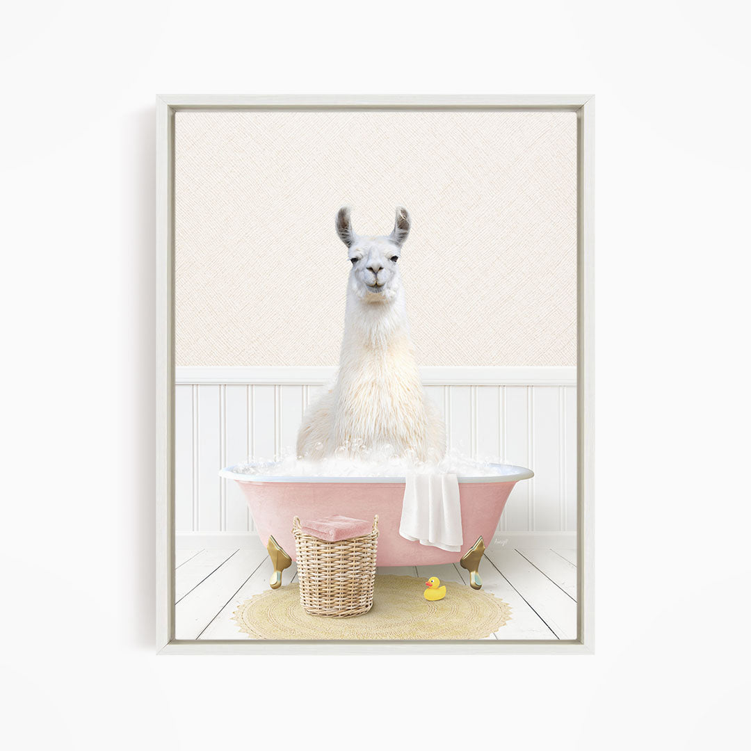 A white llama sitting in a pink bathtub filled with bubbles, surrounded by a yellow rubber duck and a wicker basket.