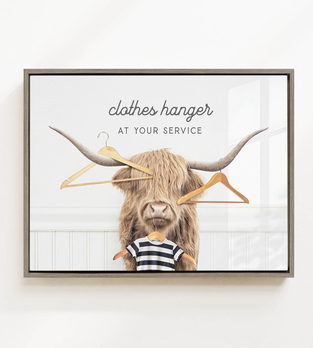 A framed image depicting a large, furry animal with long horns, wearing a striped shirt and surrounded by clothes hangers.