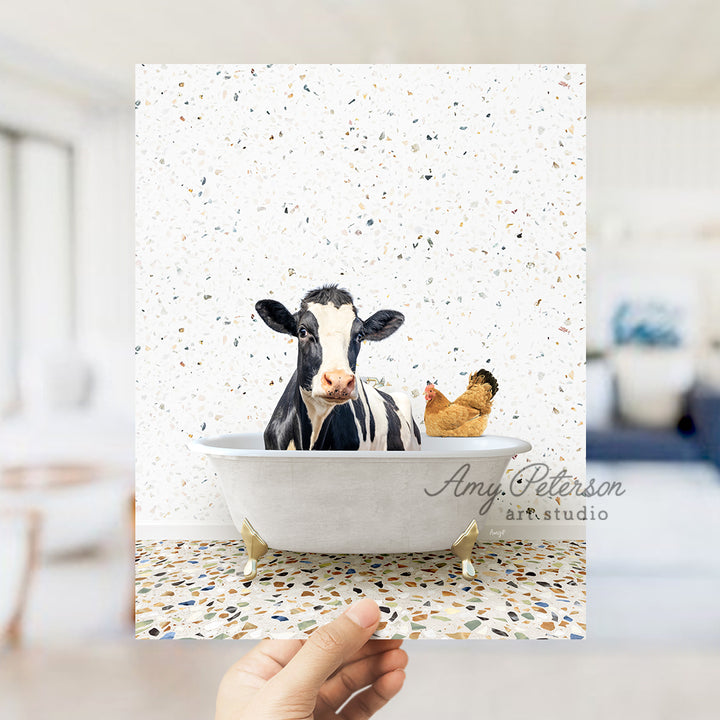 a hand holding up a card with a picture of a cow in a bathtub