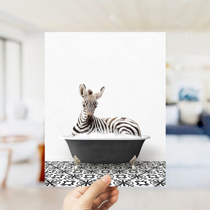 A zebra lying in a bathtub, surrounded by a black and white patterned floor.