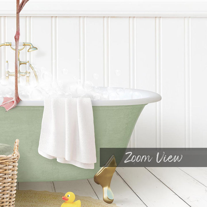 A green claw-foot bathtub filled with bubbles, with a white towel hanging on the side and a yellow rubber duck nearby.