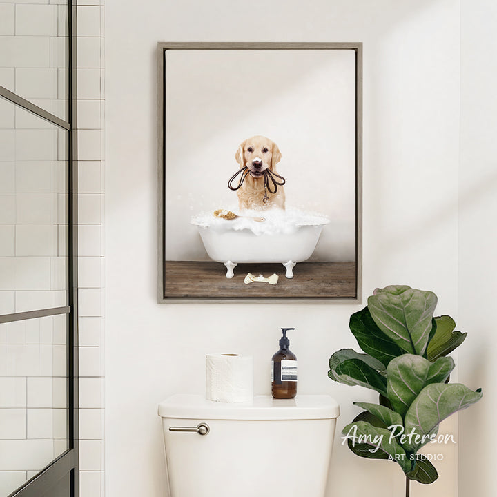 A framed image of a golden retriever dog sitting in a bathtub, surrounded by bubbles, is displayed on the wall above a white toilet in a bathroom.
