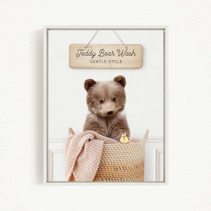 A teddy bear sitting in a woven basket, with a sign above that reads "Teddy Bear Wash Gentle Cycle".