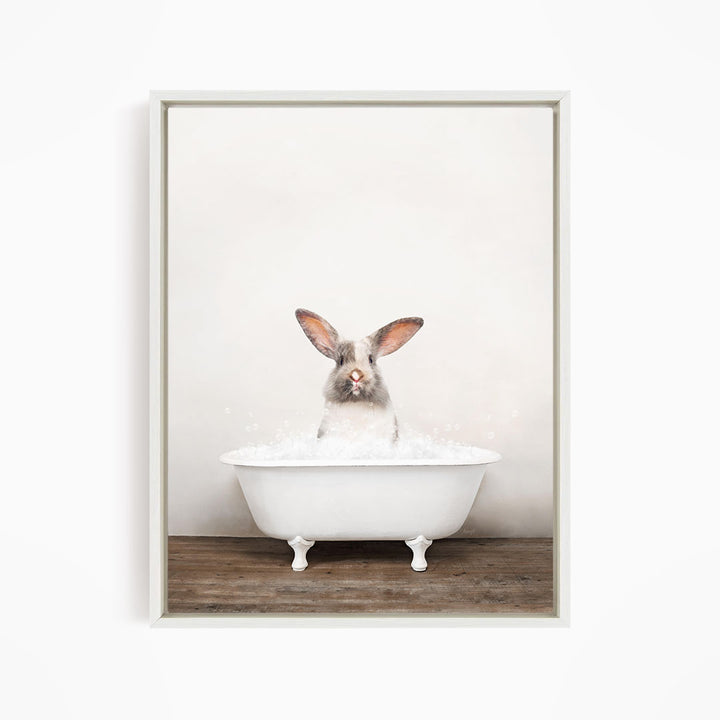 A white rabbit sitting in a white bathtub filled with water, looking directly at the camera.