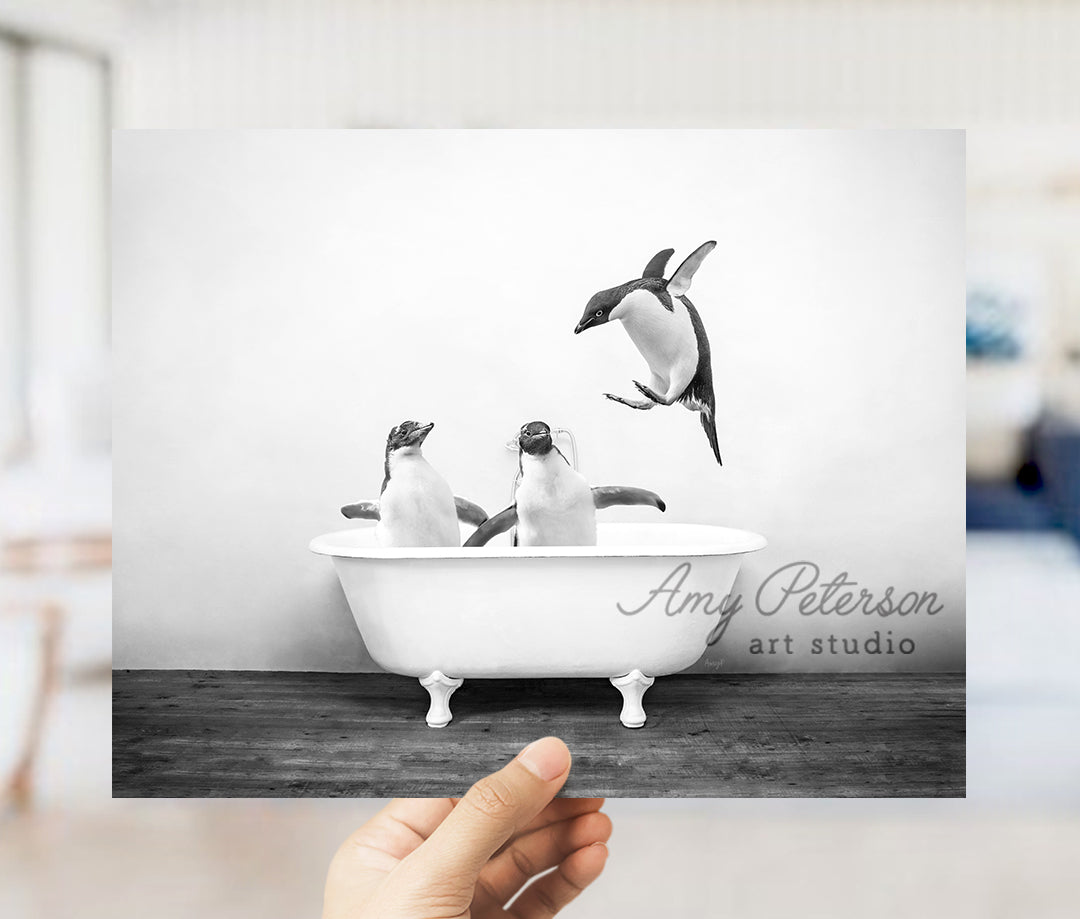 a hand holding up a photo of penguins in a bathtub