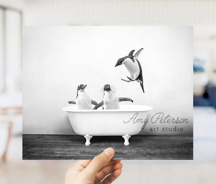 a hand holding up a photo of penguins in a bathtub