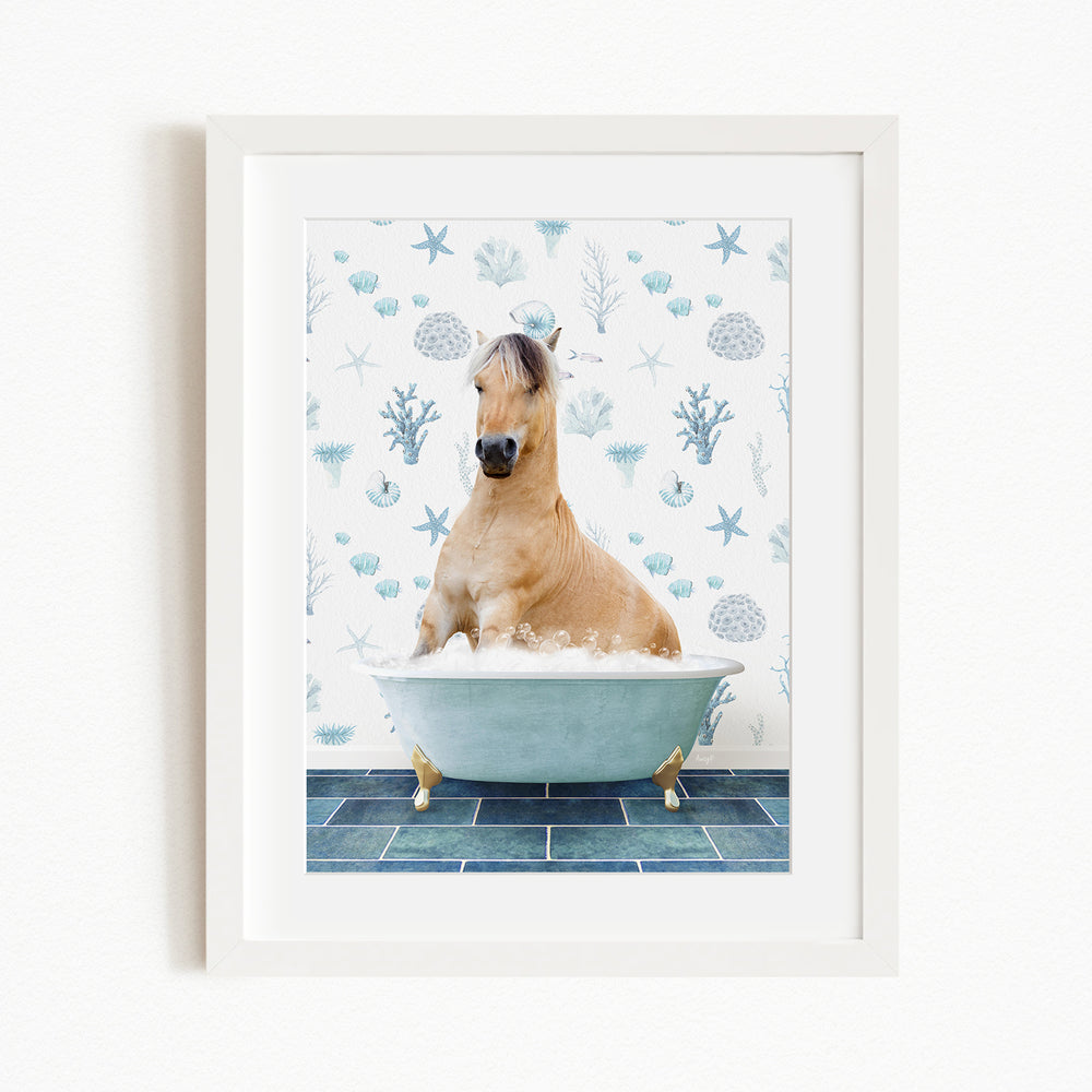 A light brown horse is sitting in a blue bathtub filled with bubbles, surrounded by a pattern of seashells and starfish on the wall behind it.