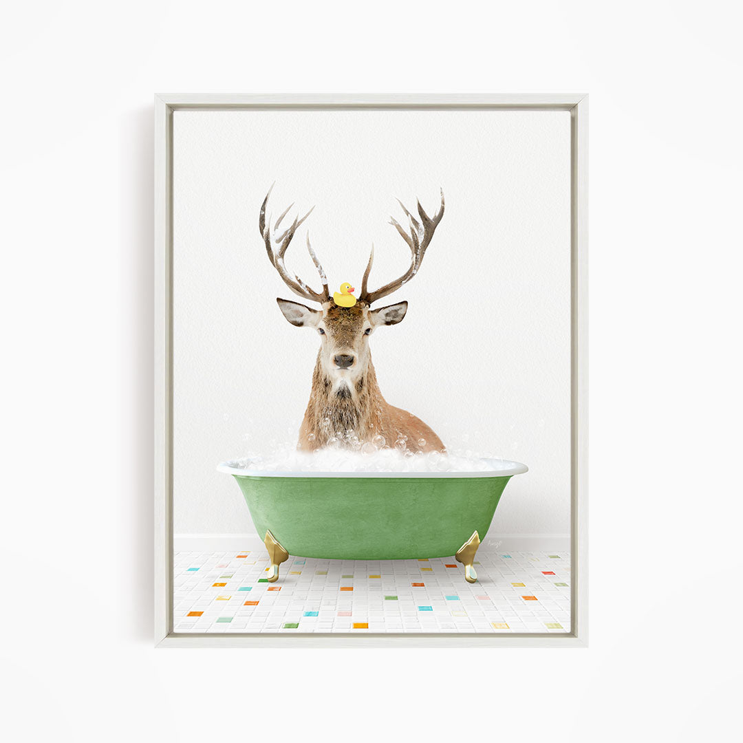 A deer with antlers is sitting in a green bathtub filled with bubbles, with a rubber duck floating on its head.