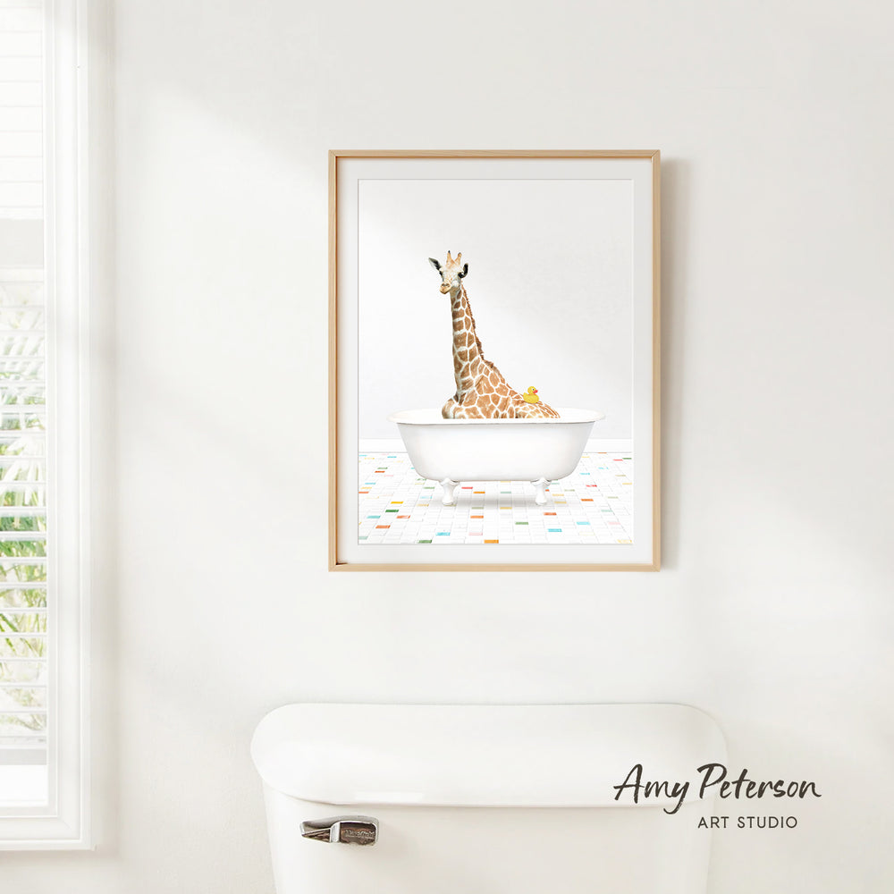 A framed illustration of a giraffe sitting in a bathtub is hanging on a white wall.