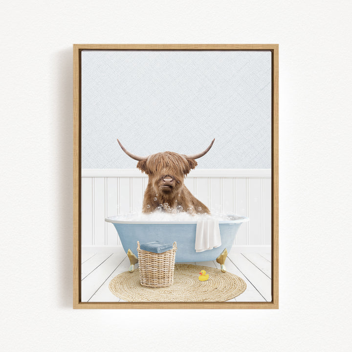 A brown cow with long horns is sitting in a blue bathtub filled with bubbles, surrounded by a basket of toys and a yellow rubber duck.