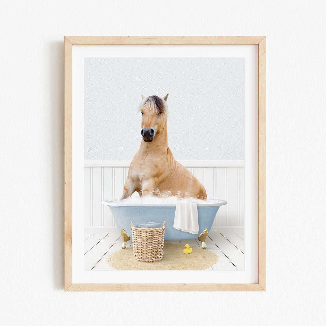 A light brown horse is sitting in a blue bathtub filled with water, surrounded by a yellow rubber duck and a wicker basket.