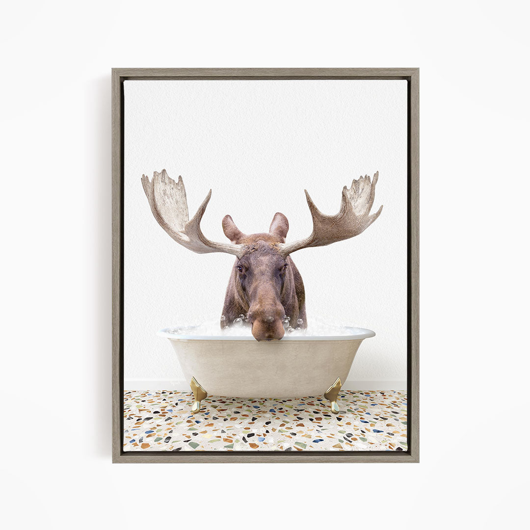 A moose with large antlers is sitting in a bathtub filled with water, creating a whimsical and humorous scene.