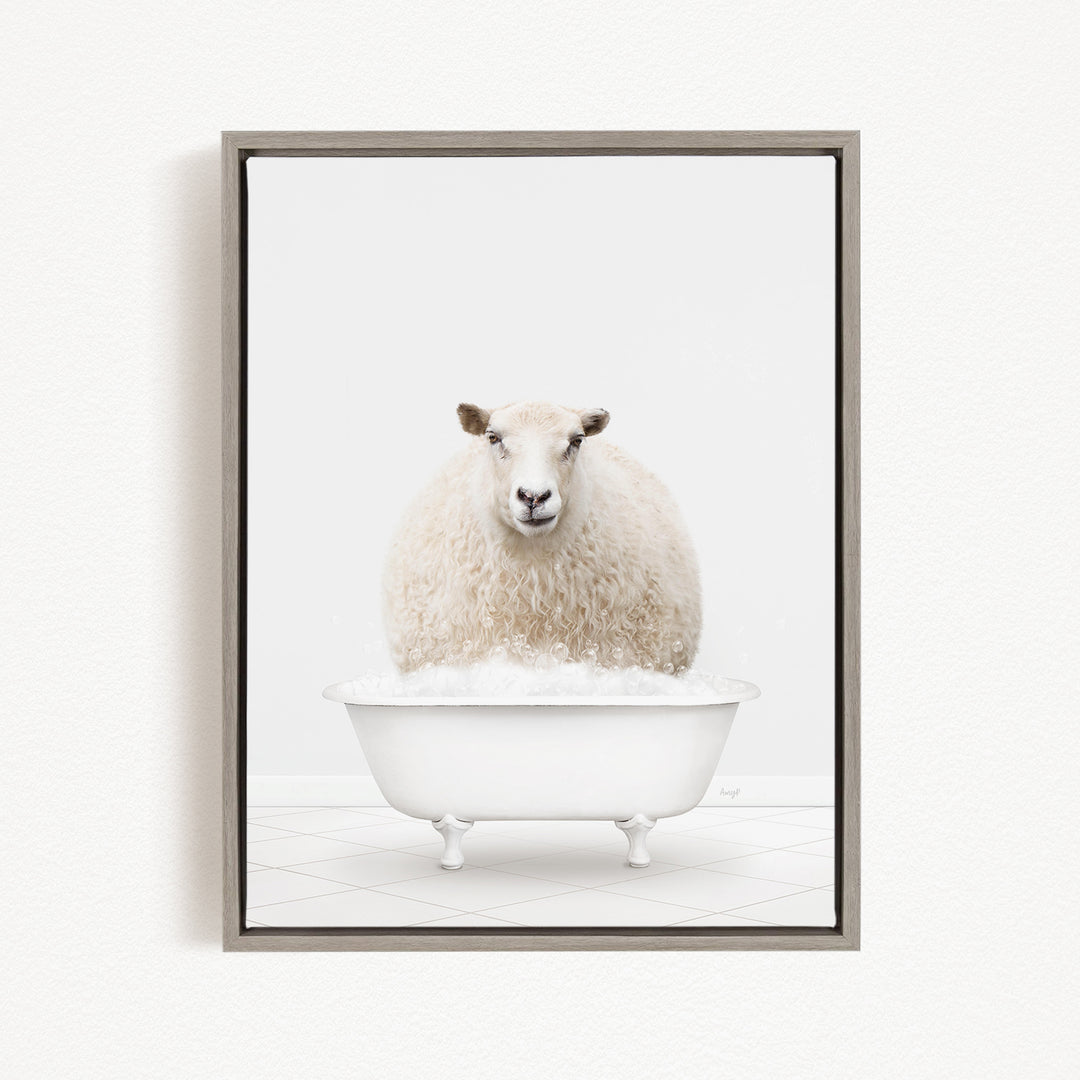A fluffy white sheep sits in a white bathtub filled with bubbles, looking directly at the camera.