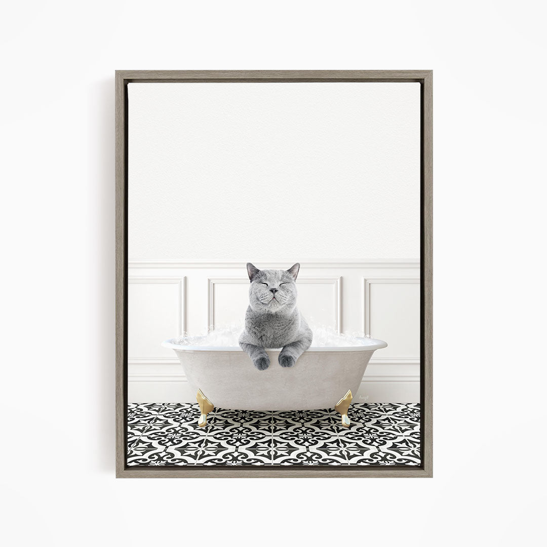 A gray cat sitting in a white bathtub filled with bubbles, with a black and white patterned floor in the background.