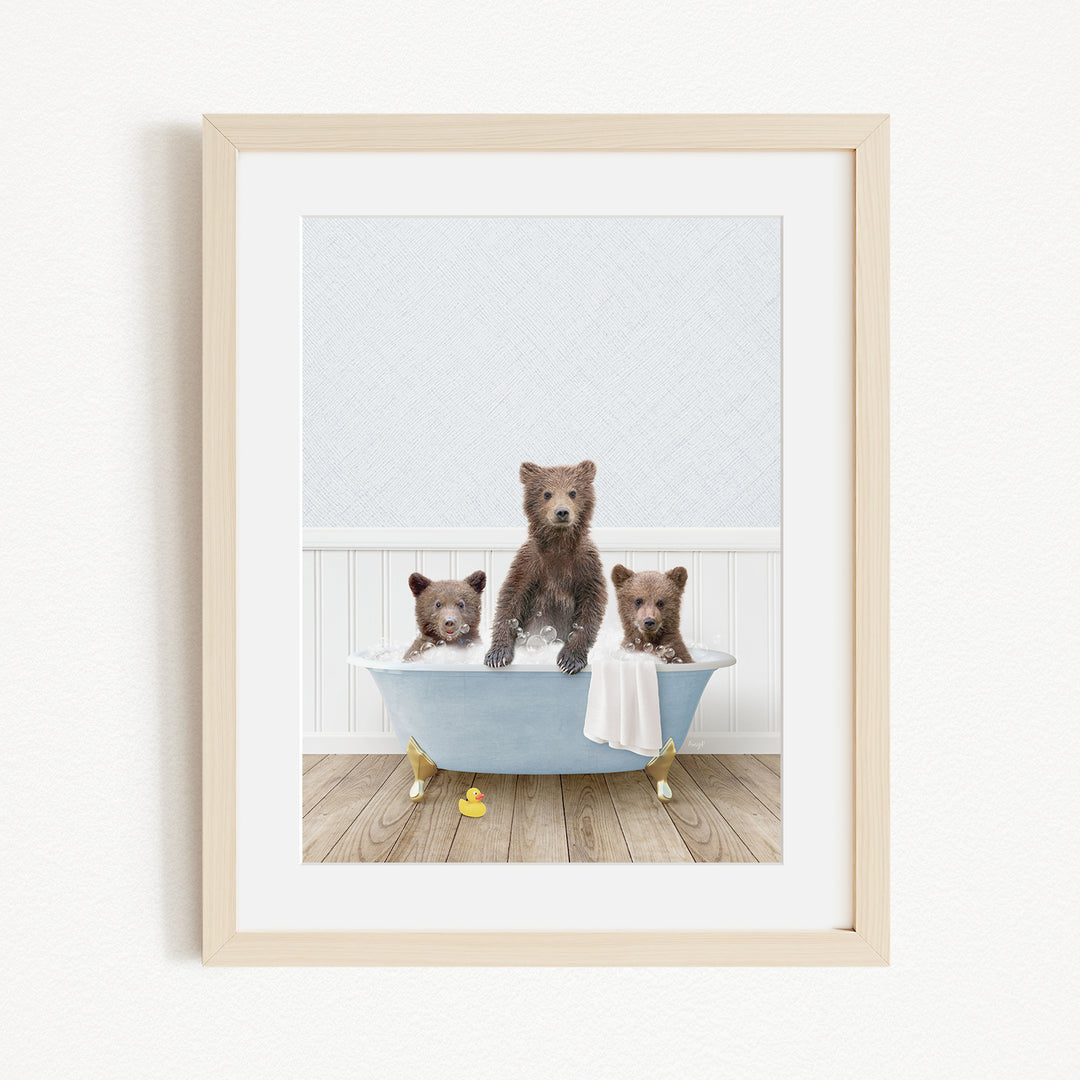 A framed image depicting three bears sitting in a bathtub, with one bear sitting on the edge of the tub and the other two bears sitting inside the tub.