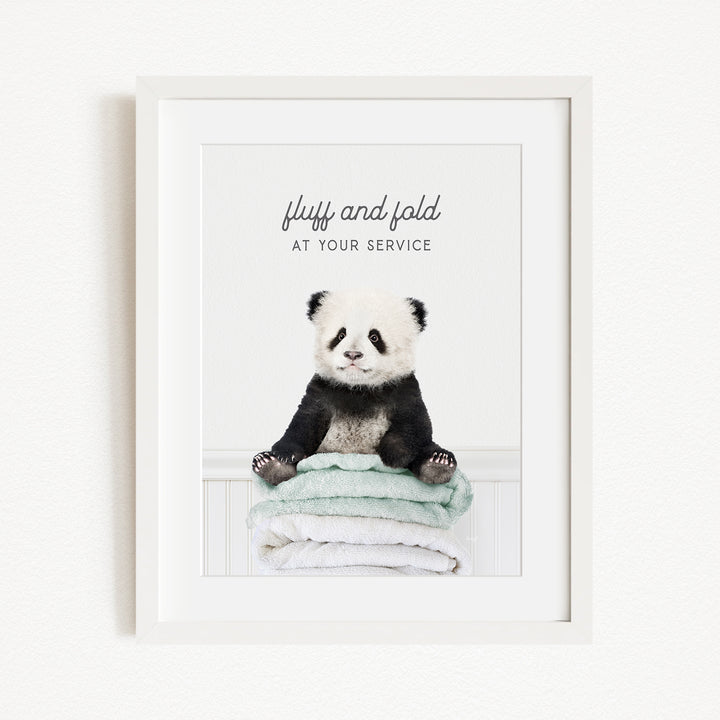 A panda bear sitting on a stack of towels, with the text "fluff and fold at your service" written above the image.