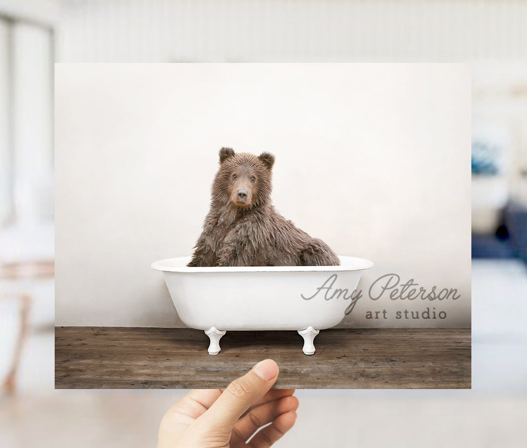 a hand holding a card with a picture of a bear in a bathtub