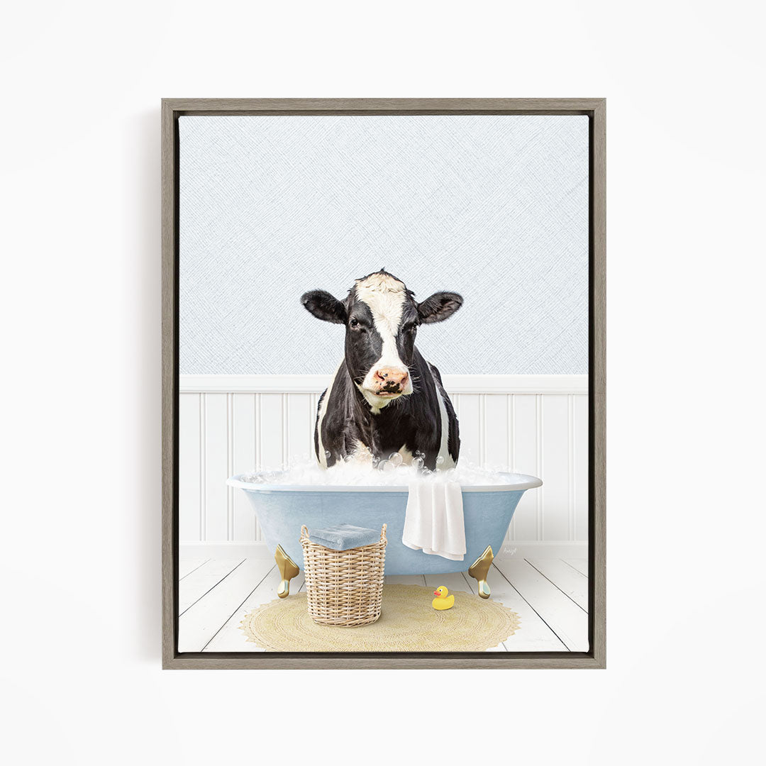 A black and white cow is sitting in a blue bathtub filled with water, surrounded by rubber ducks and a basket.
