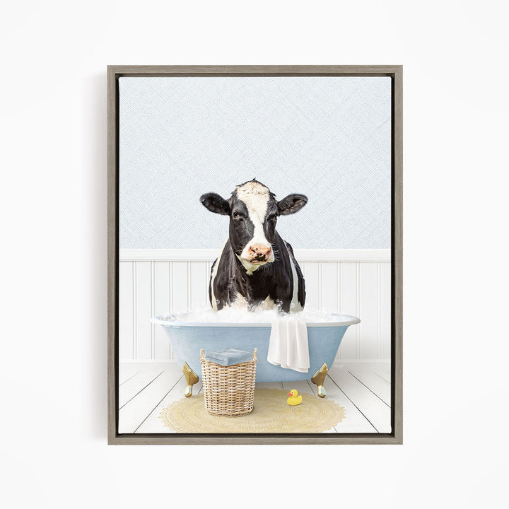A black and white cow is sitting in a blue bathtub filled with water, surrounded by rubber ducks and a basket.