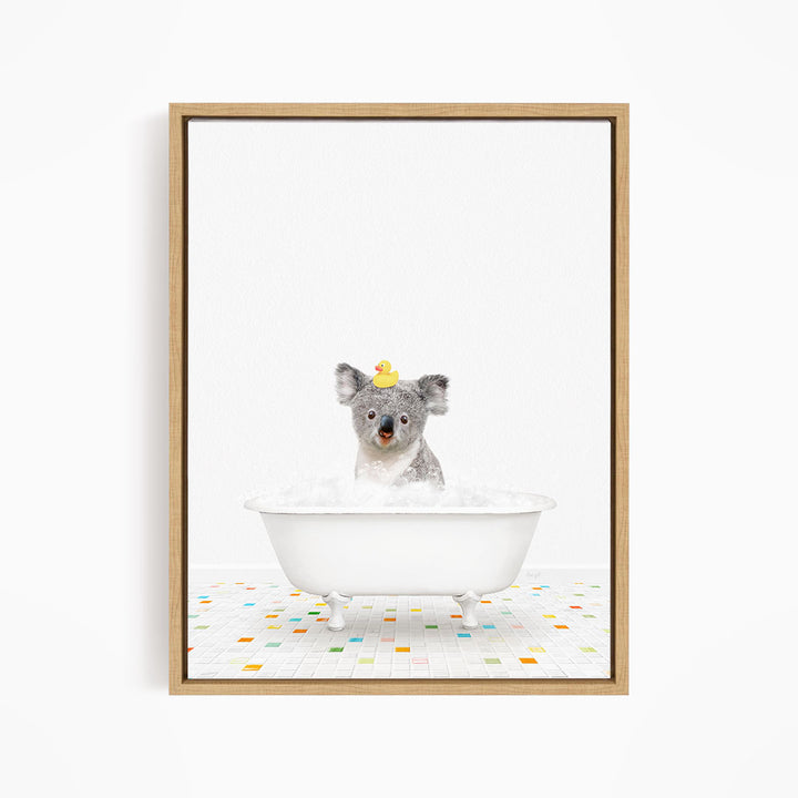 A koala bear sitting in a white bathtub filled with bubbles, with a rubber duck perched on its head.