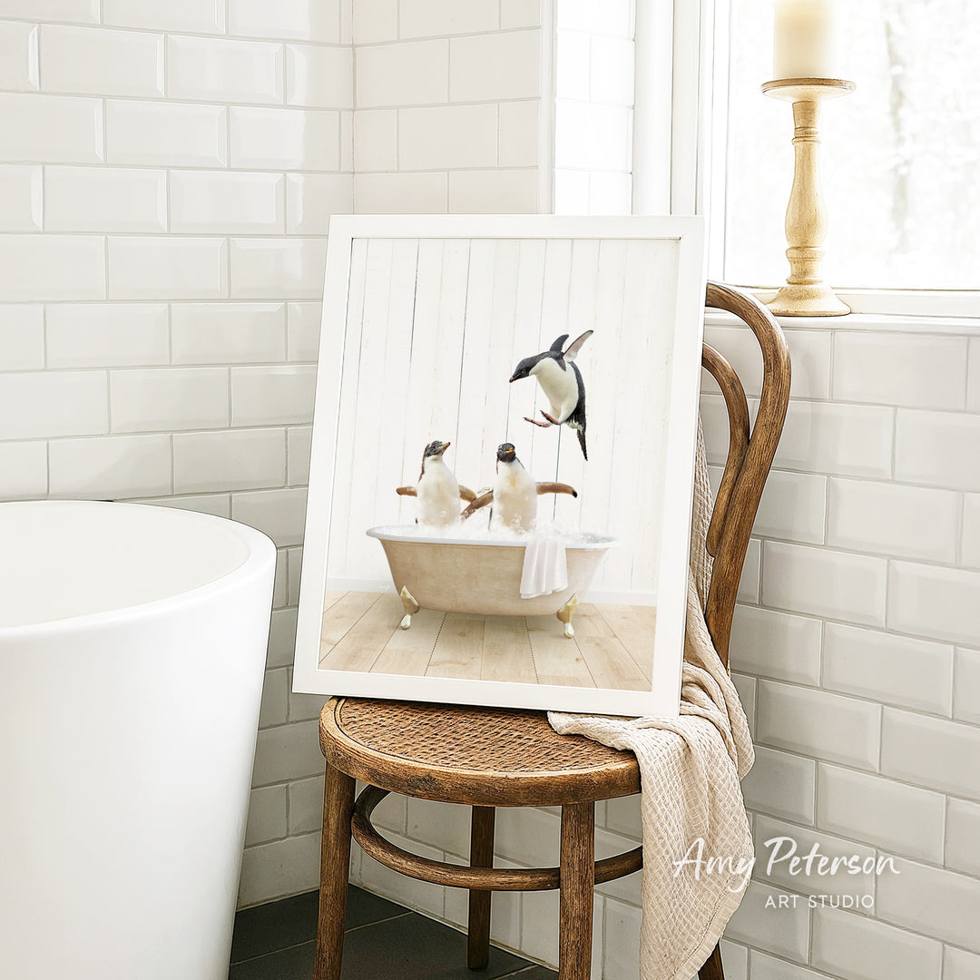 A framed image of two penguins sitting in a bathtub, with one penguin standing on its hind legs and the other sitting comfortably.